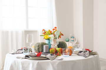 Beautiful table setting with pumpkins and autumn leaves in dining room
