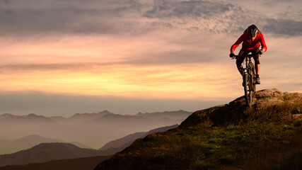 Cyclist in Red Riding Bike on the Autumn Rocky Trail at Sunset. Extreme Sport and Enduro Biking...