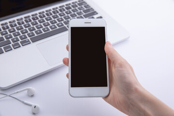 top view of female hands using smartphone over desktop with laptop , work concept . High quality photo
