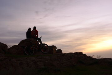 Young Couple Sitting on the Rock in the Mountains at Night