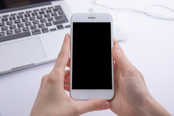 top view of female hands using smartphone over desktop with laptop , work concept . High quality photo
