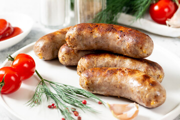 Fried sausages. Fried sausages with spices, sauce, tomatoes and parsley. Delicious meat sausages in...