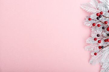 Christmas border with fir branches, rowan and golden lights on pastel pink background