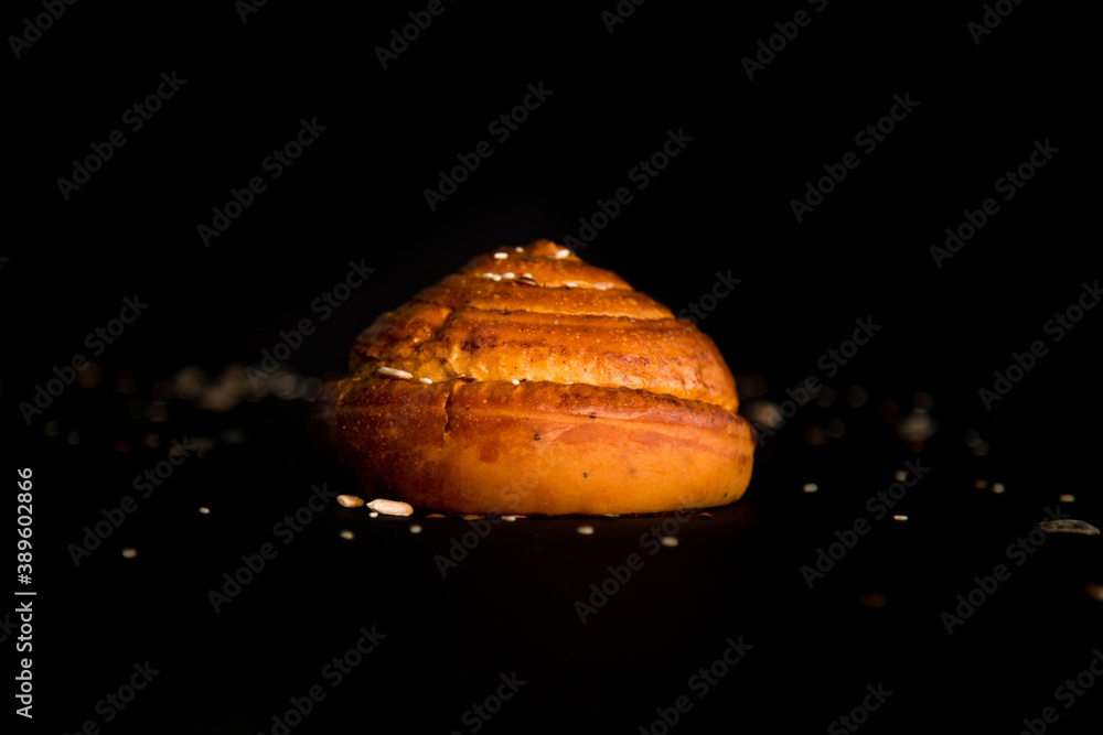 Wall mural a bread roll with seeds on black background