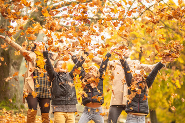 Family fun outdoors in the autumn by throwing fallen leaves up in the air - Powered by Adobe