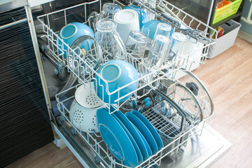 opened Dishwasher after cleaning process both baskets with clean dishes: bowls, glasses