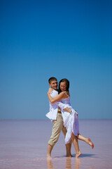 A couple a man and a woman dance on a pink lake on a Sunny day