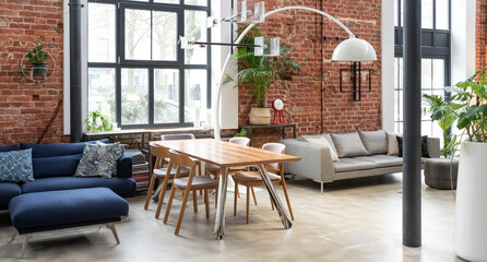 Interior of living room in industrial style in loft apartment. Brick wall, big wall, wooden table and navy sofa in stylish room at home. Banner.