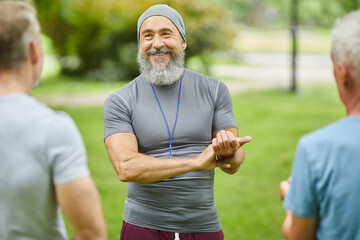 Modern fitness trainer standing in front of senior clients demonstrating them how to check heart...