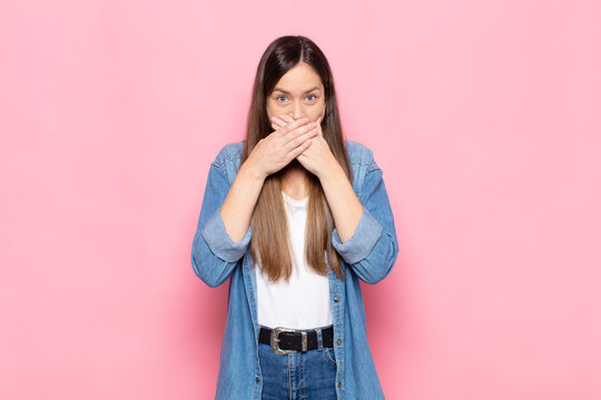 young pretty woman covering mouth with hands with a shocked, surprised expression, keeping a secret or saying oops
