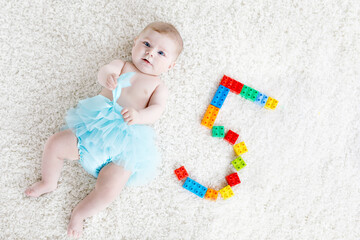 Adorable baby girl on white background wearing turquoise tutu skirt.