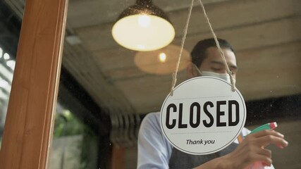 An Asian man cleans the door of a shop preparing to reopen the store after being shut down during the covid 19 epidemic.