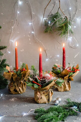 Red advent flower arrangement with three burning candles