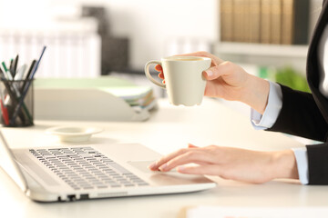 Fototapeta na wymiar Executive hands holding coffee using laptop at office