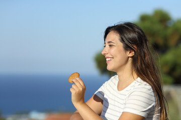 Happy woman holding cookie in a balcony on the beach