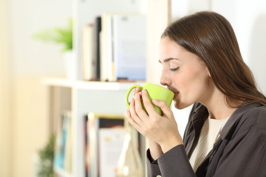 Woman drinking coffee from mug at home