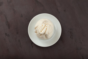 Fresh Italian cheese. White ball of burrata or burratina cheese made from mozzarella and cream filling. Top view, selective focus, copy space, brown background