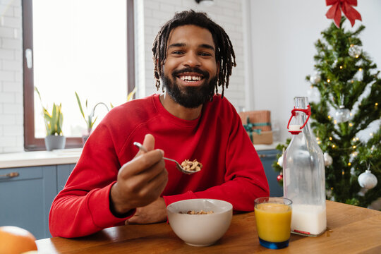 Joyful african american man eating cereal while having breakfast