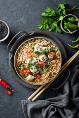 Asian noodle soup, ramen with tofu and vegetables on dark background, top view