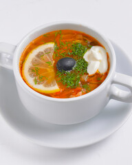Ukrainian beetroot soup - borscht with sour cream served in a white bowl over white background.