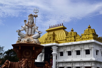 Fototapeta na wymiar Shiva statue near hinduism temple with bright golden roof. Sri Ramayana Darshanam & BharatMata Sadanam, Kanyakumari, India