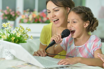 Portrait of smiling mother and daughter singing karaoke