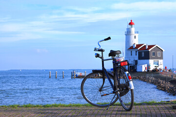 Blue sea harbor with bicycle parked on cobble stone pier against lighthouse on the seacoast....