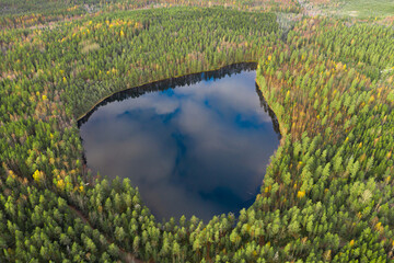 Heart-shaped lake with blue water and green and dense pine forest. Photo from the drone. Finland,...