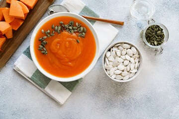 Top view of pureed pumpkin soup in a white bowl on dark table