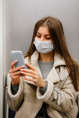 a young woman of European appearance in a mask looks at the phone.
