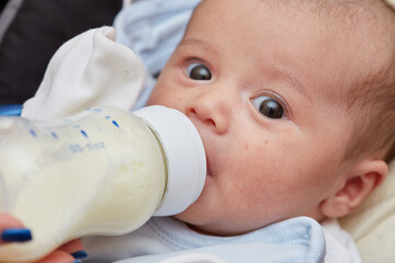 2-month-old newborn baby close-up . there is baby food, milk from a bottle. small depth of focus area . selective focus