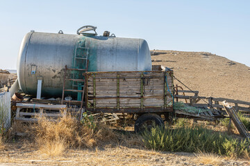 old abandoned trailer in the mountains next to a corral. it's made of wood and rusty iron