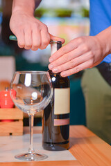Wine glass and bottle of red wine on a wooden table over blurred background. Restaurant service, eating out concept.