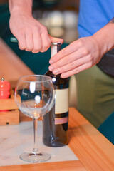 Wine glass and bottle of red wine on a wooden table over blurred background. Restaurant service, eating out concept.
