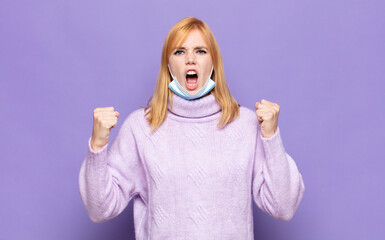 pretty woman  shouting aggressively with an angry expression or with fists clenched celebrating...