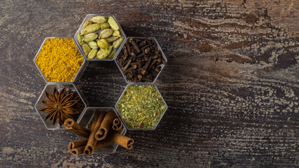 Spices in hexagonal jars on a wooden surface