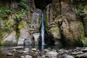 narrow waterfall falls between rocky stone walls