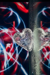 Crystal glass heart on light bright colorful background. Blue and red light leaks abstract image, reflection in the mirror 