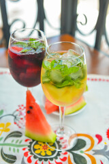 Glasses of red wine and white wine with watermelon pieces on the table. Delicious cold fruit drink served in glasses.