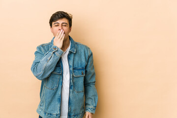 Young cool man yawning showing a tired gesture covering mouth with hand.