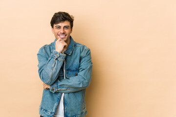 Young cool man smiling happy and confident, touching chin with hand.