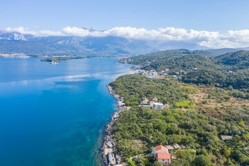 Fototapeta na wymiar Aerial photo of the coastline of the Adriatic sea bay, small Montenegrin town in autumn. Sunny day, blue sky, mountains are visible in the distance. Water in the sea is turquoise, pure and clear