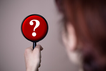 Female person holding a mirror with question mark in it