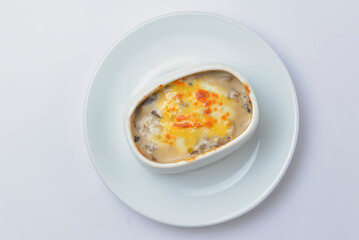 Roasted vegetables, potatoes, mushrooms and cheese in a pot. Baked dinner in a white pot. Delicious meal for dinner.