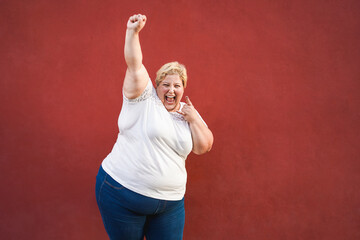 Happy and excited plus size woman celebrating with success and winning gesture - Focus on face