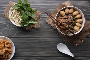 Asian noodles with pork, pork balls, pork crackling and vegetables on dark background. Close up Thai boat noodle culture style top view and flat lay with copy space for your advertising content.
