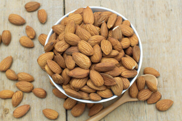 Almond nuts in white bowl with wooden spoon on wooden background,selective focus.vegetarian food.flat lay,top view,top down.