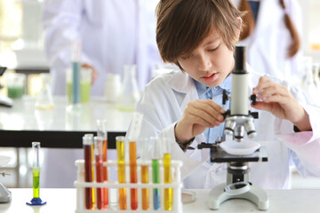 happy little boy making science experiments with test tube and microscope (education and scientist concept)