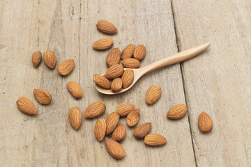 The almonds are in a brown wooden spoon and several seeds around which are on a wooden background.vegetarian food.flat lay,top view,top down.