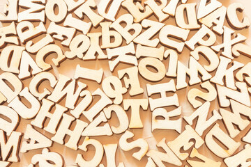 Wooden English letters are scattered over the light surface. Concept for alphabet, writing and journalism, storytelling, learning.